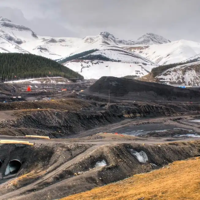 A mining site with snow covered mountains in the background.