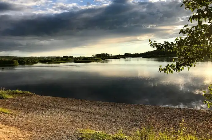 A tranquil riverbank with clouds in the sky